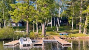 A calm lake with wooden docks and boats. - Camp Quality Time on Wilson Lake 3-bedroom, hot tub (Wilton)