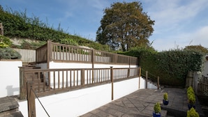 Une terrasse extérieure à plusieurs niveaux, avec un revêtement de sol en pierre, une rambarde en bois et des plantes en pot.