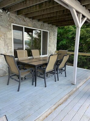 An outdoor patio with a stone wall, a covered seating area, and a view of greenery.