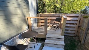 A patio with a wooden deck, a small table, and two chairs.