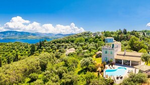 Eine Villa mit Pool, umgeben von üppiger Vegetation und Blick auf das Meer.