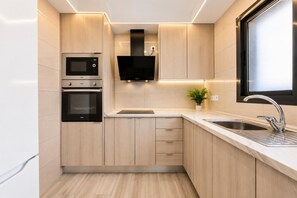 Una cocina moderna con electrodomésticos integrados, un lavamanos y un ventanal.