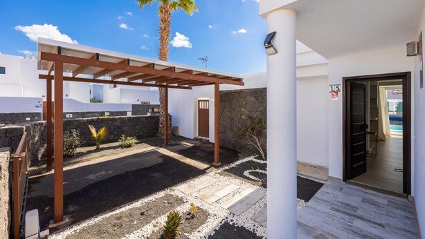 Un patio extérieur moderne agrémenté d’une pergola, d’un palmier et d’un mur en pierre.