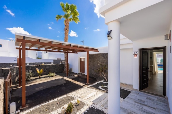 Un patio extérieur moderne agrémenté d’une pergola, d’un palmier et d’un mur en pierre.