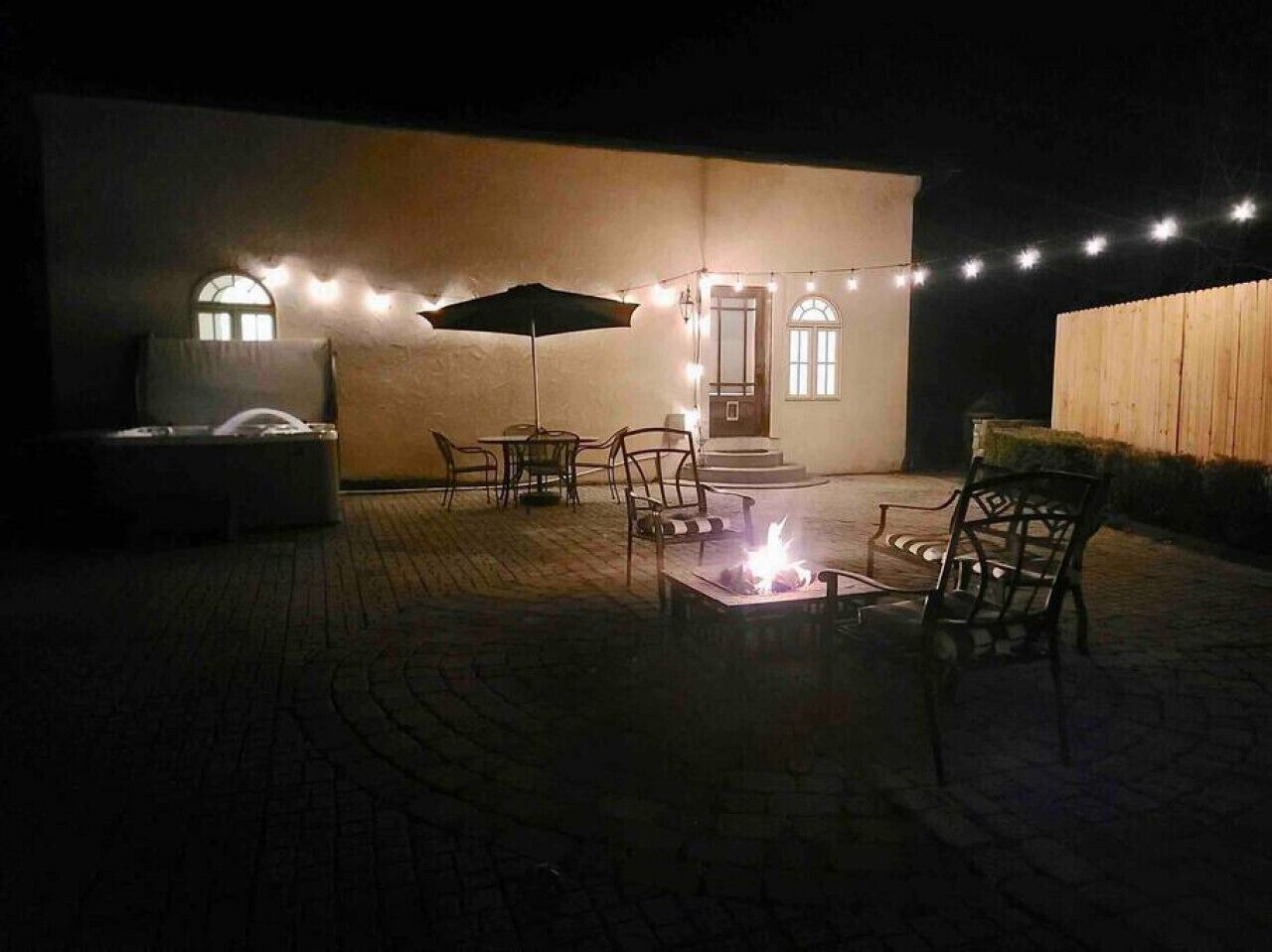 Un espace extérieur aménagé en terrasse, avec un foyer, des chaises et un parasol.
