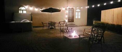 Un espace extérieur aménagé en terrasse, avec un foyer, des chaises et un parasol.