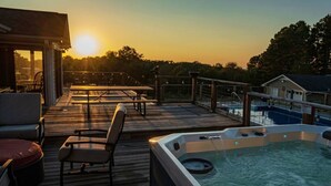 A deck with outdoor seating and a hot tub overlooking a pool.