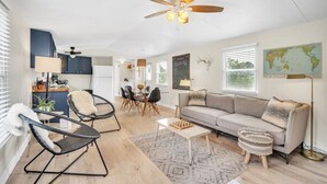 A spacious living area with a sofa, chairs, a coffee table, and a dining table.
