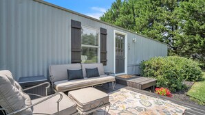 A mobile home with a patio area featuring a sofa, chairs, and a rug.