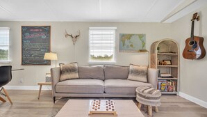 A cozy living room with a sofa, coffee table, and a guitar.
