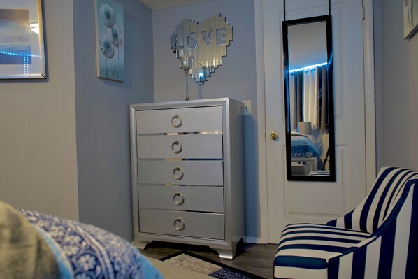 A bedroom with a dresser, a mirror, and a striped chair.