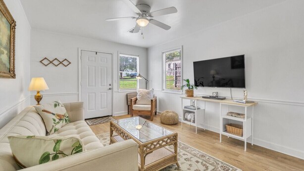 A living room with a sofa, coffee table, TV, and a ceiling fan. - Cozy, Bright Suite w/ King Bed (Travelers Rest)