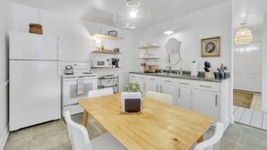 A modern kitchen with white cabinets, a wooden dining table, and various kitchen appliances. - Cozy, Bright Suite w/ King Bed (Travelers Rest)