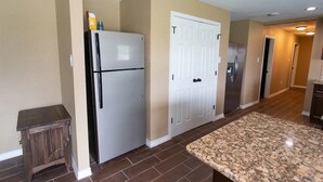 Une cuisine équipée d’un réfrigérateur, d’un meuble à deux portes et d’un plan de travail en granit.