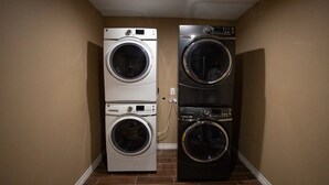 Une buanderie équipée de deux machines à laver et de deux sèche-linge à chargement frontal, placés l’un sur l’autre.