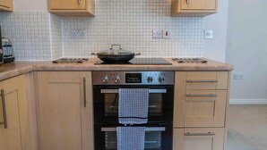 A kitchen with wooden cabinets, a tiled backsplash, a stove, and an oven. - Closetocitycentre&nec-business&family-freeparking (Solihull)