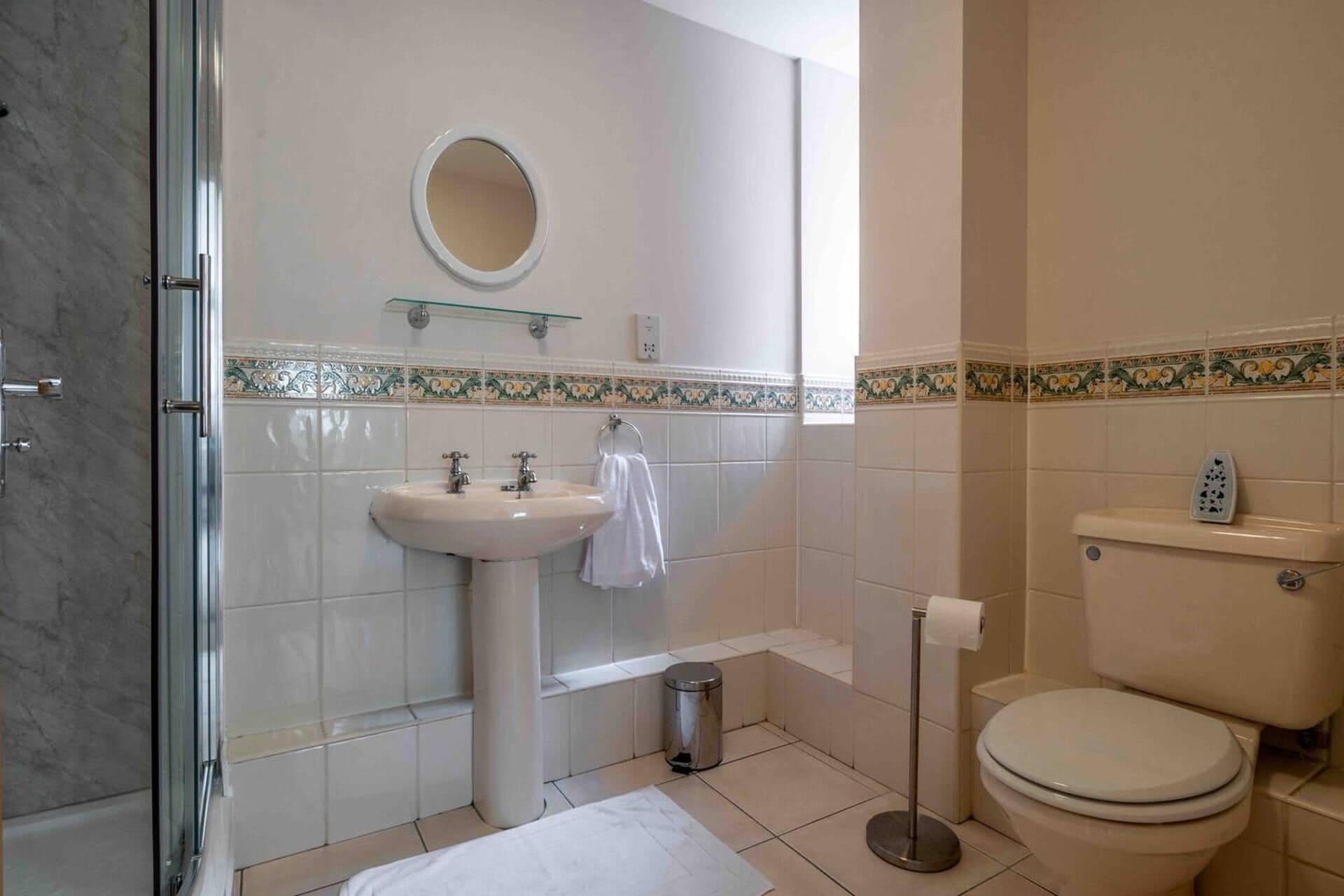 A bathroom with a sink, mirror, toilet, and shower.