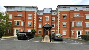 A multi-story residential building with a central entrance, parking spaces, and a small covered area. - Closetocitycentre&nec-business&family-freeparking (Solihull)
