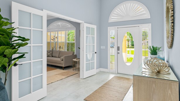 Un interno moderno con un'ampia porta aperta su una zona living, un tavolino da caffè in vetro e un elemento decorativo a parete.
