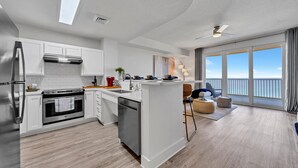 A modern kitchen with white cabinetry, a central island, and a view of the ocean through large windows.