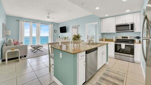 A modern kitchen with white cabinets, a granite countertop, stainless steel appliances, and a view to the outside.