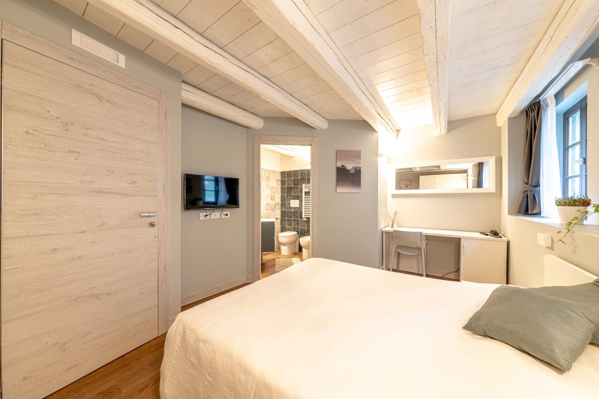 A bedroom with a bed, a desk, and a television.