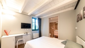 A bedroom with a bed, a desk, a chair, a TV, and a bathroom visible through an open door. - Hotel Mura 5&7 (Trieste)
