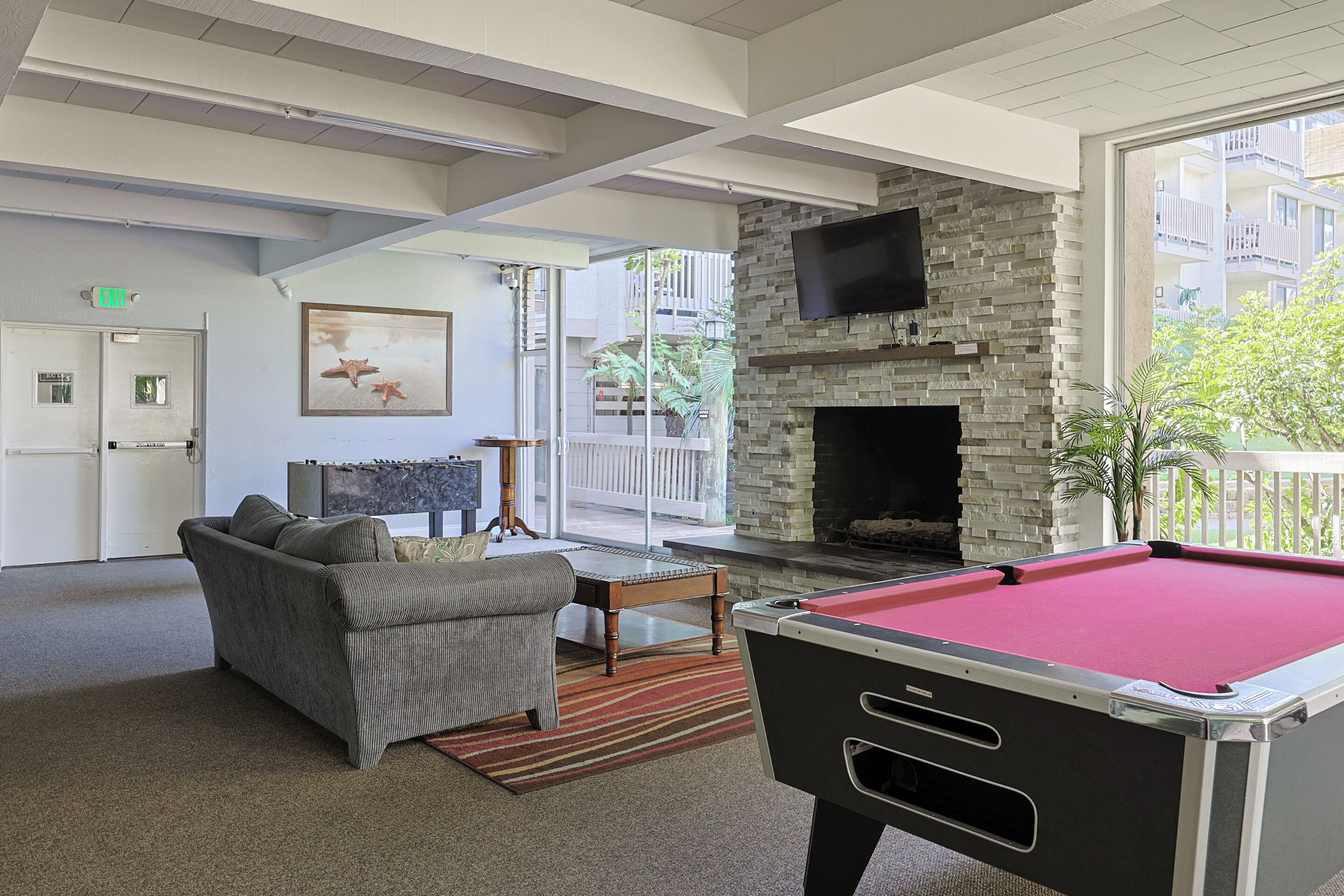 A pool table, a sofa, a fireplace, and a TV in a modern lounge area.