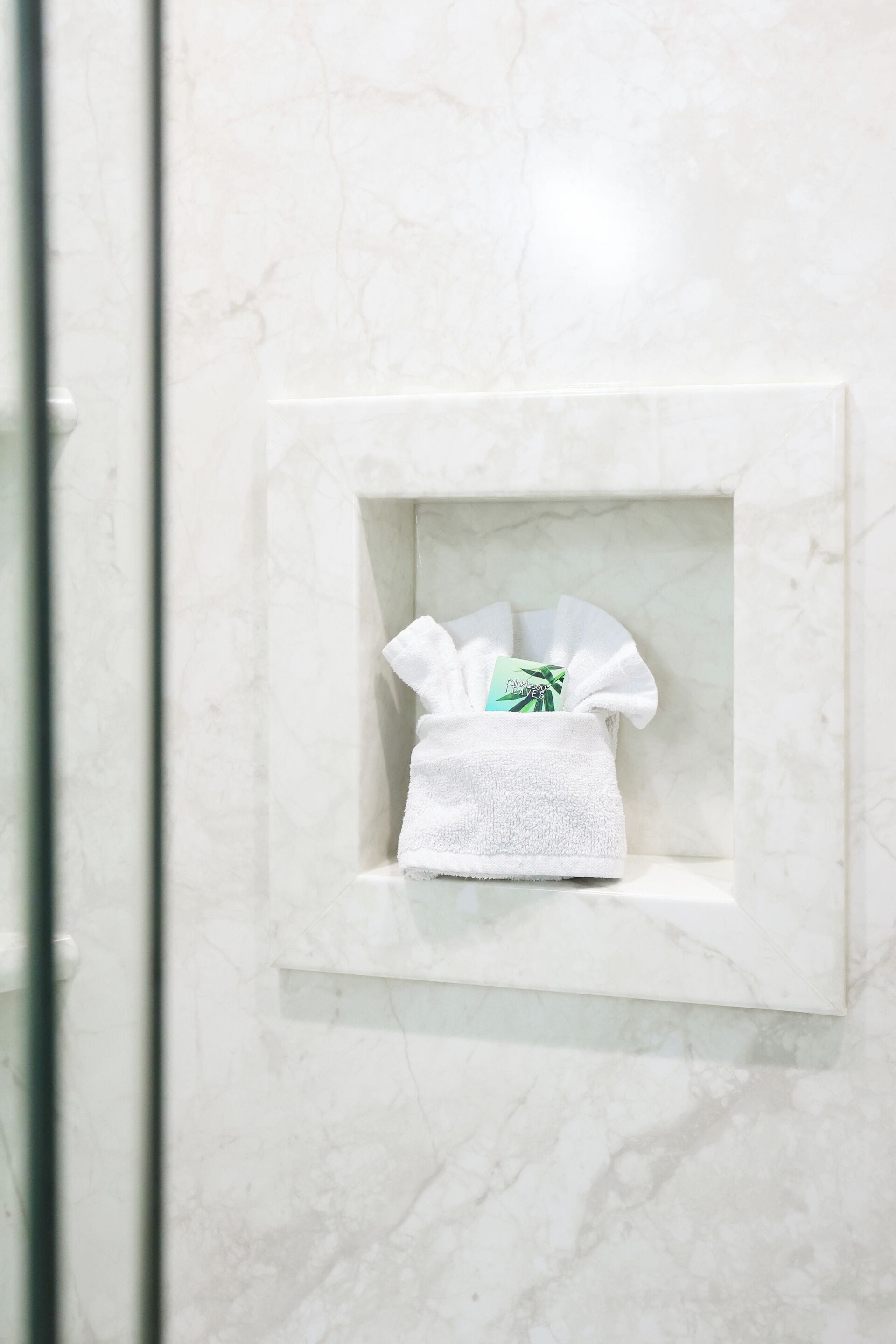 Un baño con pared de mármol y dispensador de toallas blanco.