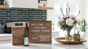 A kitchen counter with a welcome sign, a bottle of wine, and a vase of flowers.