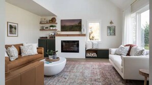 A living room with a fireplace, two sofas, a coffee table, and a patterned rug.