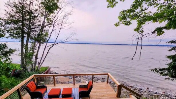 A wooden deck with outdoor seating and a view of the water.