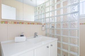 A bathroom with a white sink, a mirror, and a glass shower enclosure. - L'Agave Nantaise - Jolie maison à 15min de Nantes (Vertou)