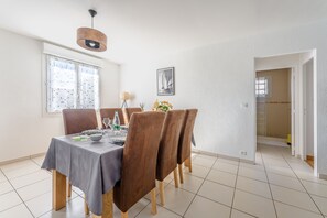 A dining area with a table set for four, wooden chairs, a pendant light, and a window with frosted glass. - L'Agave Nantaise - Jolie maison à 15min de Nantes (Vertou)