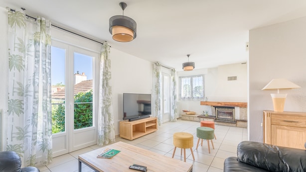Ett modernt vardagsrum med en TV, ett soffbord i trä och en svart lädersoffa.