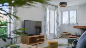 Ett vardagsrum med en tv på ett träställ, en soffa och ett soffbord.