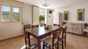 Un coin repas avec une table et des chaises en bois, un réfrigérateur et un meuble de rangement.