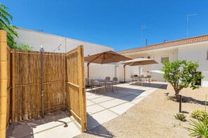 A courtyard with a bamboo fence, outdoor seating, and a tree.