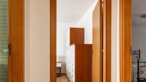 Un couloir avec des portes en bois menant à une chambre à coucher qui contient un lit et une commode.