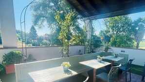 Une terrasse extérieure avec une table et des chaises, entourée de plantes en pot et offrant une vue sur le paysage.