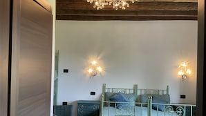 Une chambre à coucher comprenant un lit, deux tables de chevet, une commode, une chaise et un lustre.
