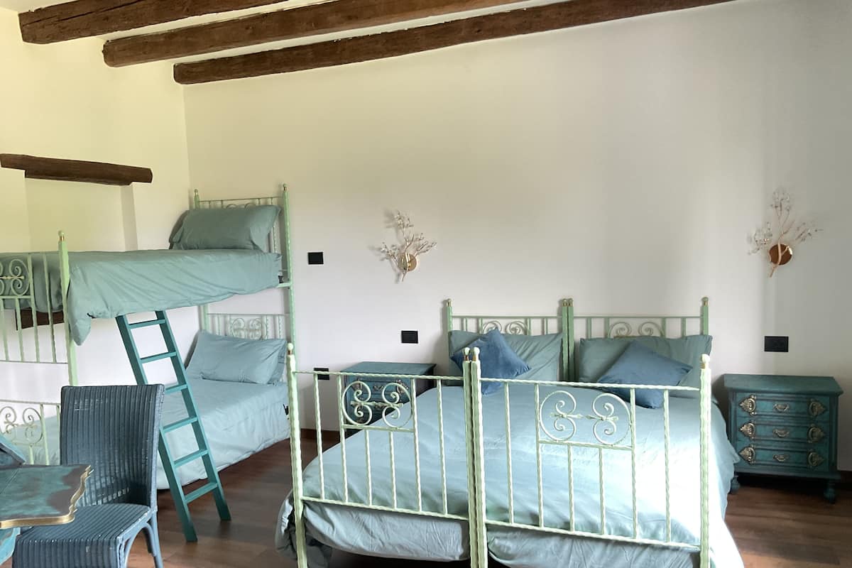 A dormitory room with bunk beds, a chair, a dresser, and decorative wall pieces.