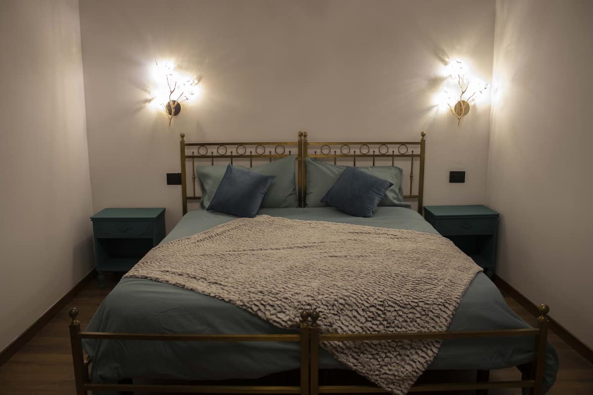A bed with a headboard, two bedside tables, and two wall-mounted light fixtures.