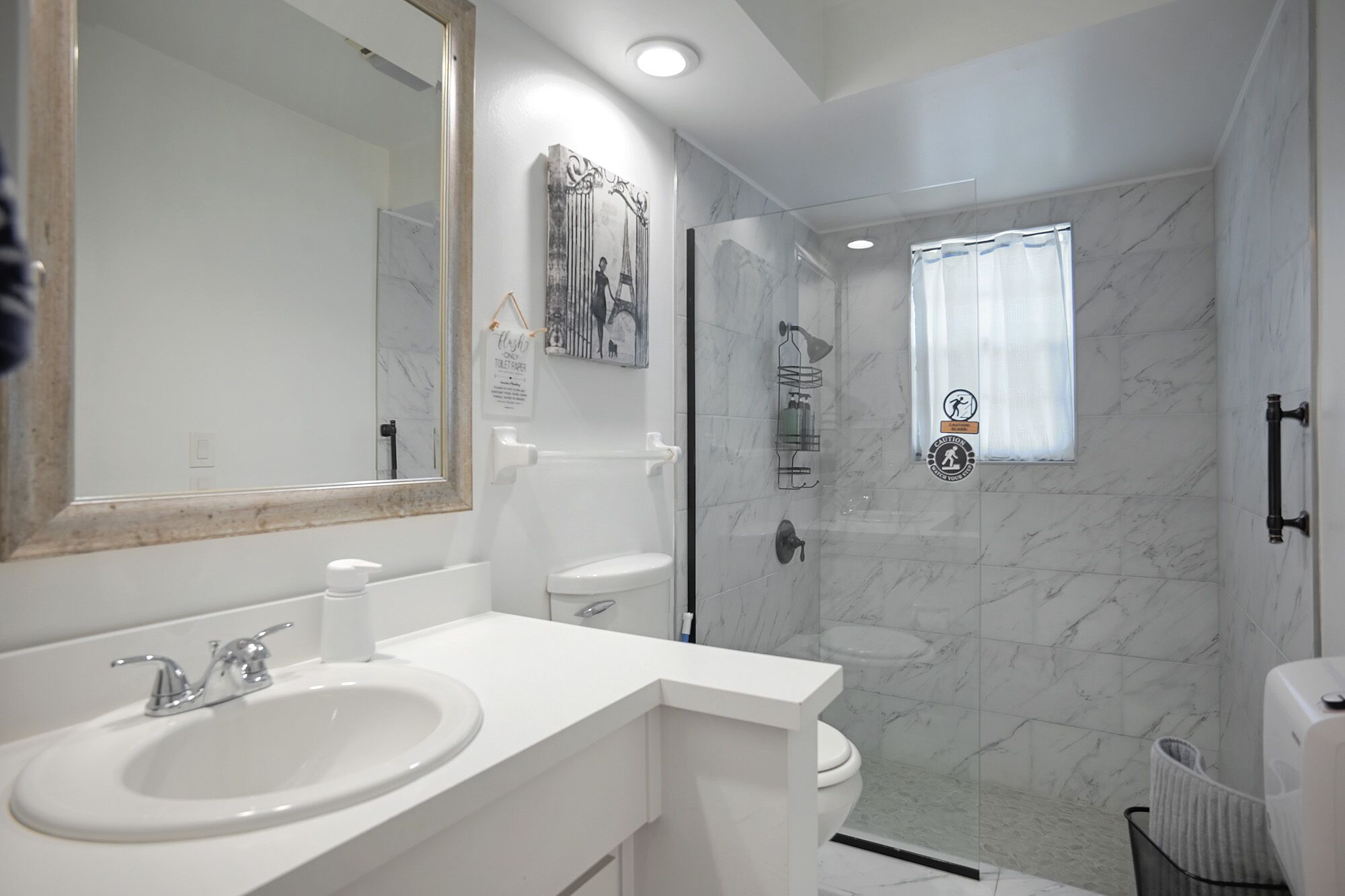 Un baño moderno con un espejo grande, un lavabo blanco y una zona de ducha.