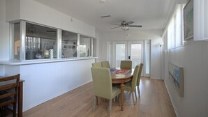 A dining area with a wooden table, four chairs, a ceiling fan, and a window with blinds. - Renae Hunt Property (Merritt Island)