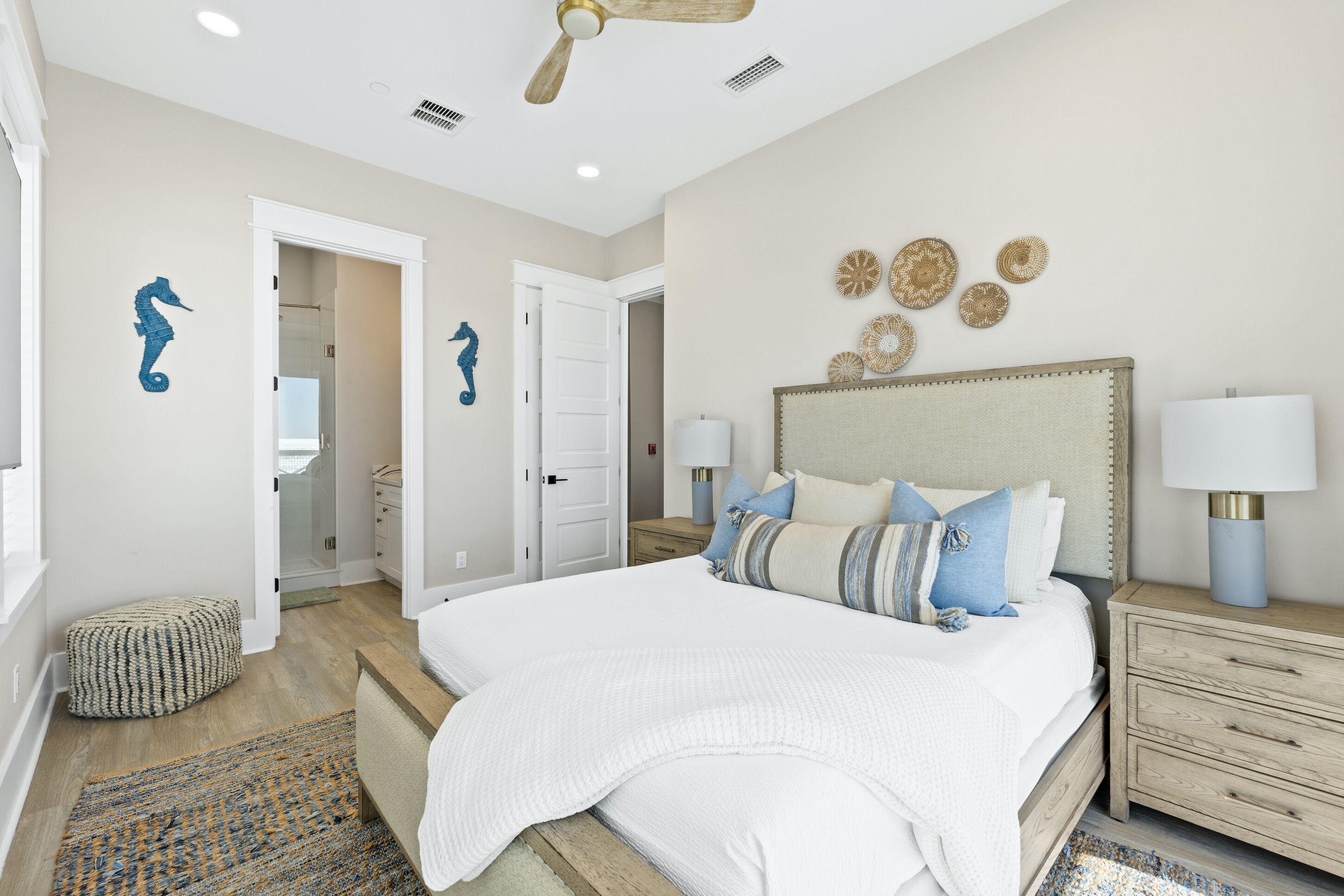 A bedroom with a large bed, a nightstand, a ceiling fan, and decorative wall art.