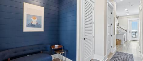 Ein modernes Interieur mit dunkelblauer Akzentwand, einem blauen Sofa, einem kleinen runden Tisch und einer weißen Tür, die auf einen Balkon führt.