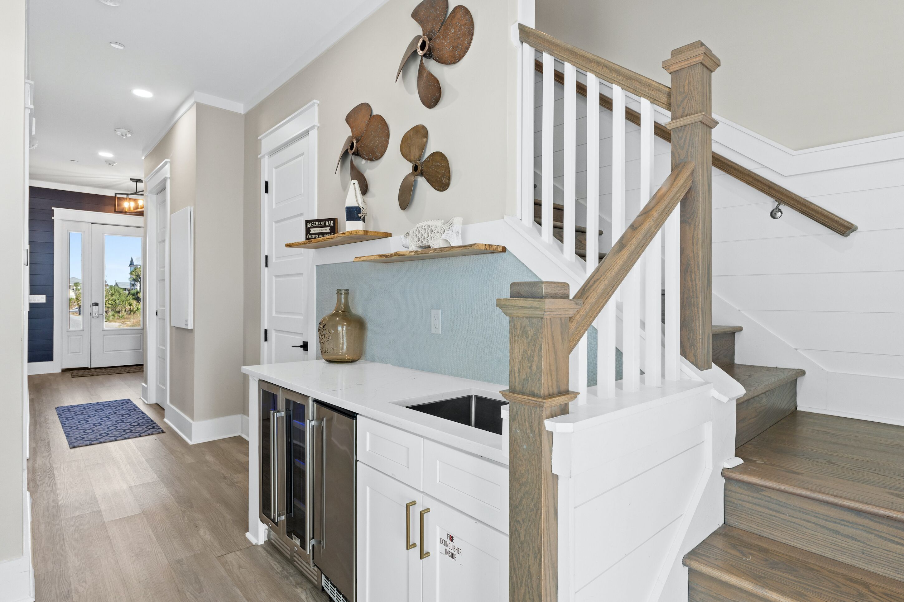 A kitchen with white cabinetry, a wooden staircase, and a view to the outside.
