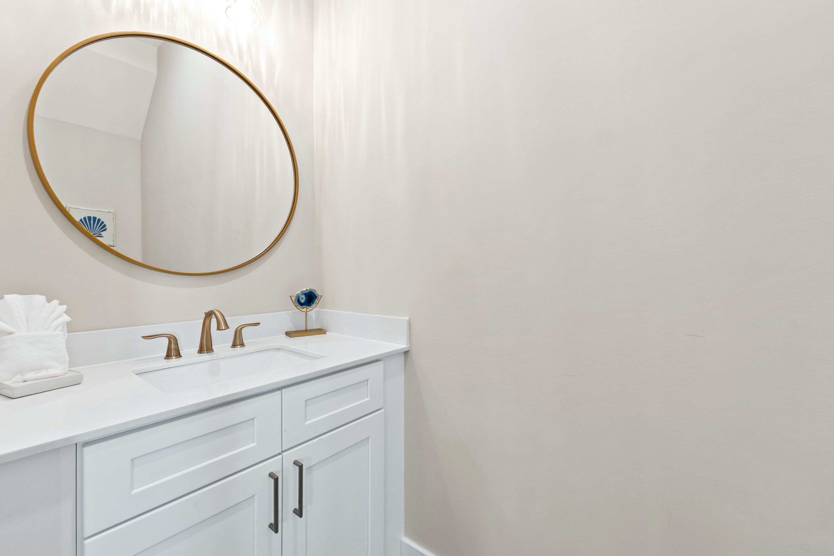 Een badkamer met een wit wastafelmeubel, een spiegel met gouden lijst en een blauwe wereldbol decoratie.