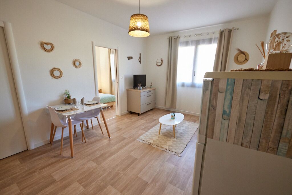 Una sala de estar moderna con comedor, piso de madera, una mesa de centro redonda y una lámpara colgante.